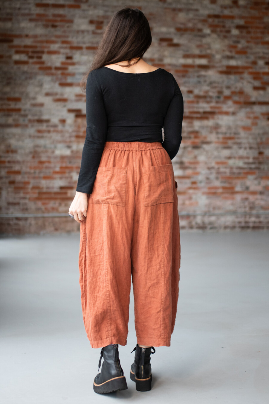 Meg McElwee wearing a black Stasia Tee and clay Arthur Pants, viewed from the back.