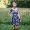 Meg McElwee wearing a floral Stasia Dress in a green field