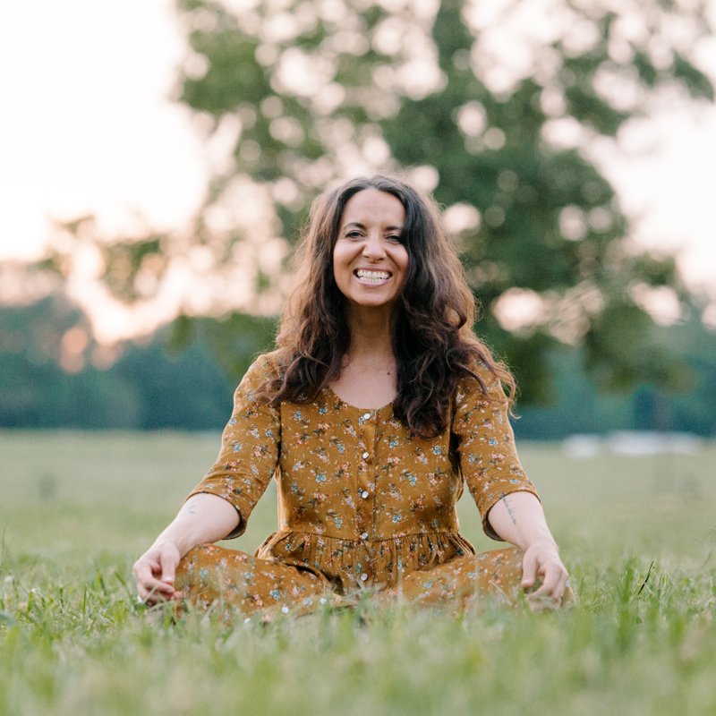 Meg McElwee smiling in a green field wearing a yellow Hinterland Dress