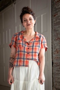 Meg wearing a red plaid, view a Joanie Top