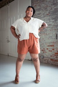 Ashley wearing red chanterelle shorts and a cream Joanie top